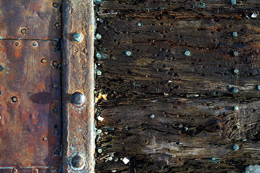 Rusty weathered iron with rivets and rotted wooden boards suitable as background image