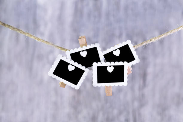 Group of black chalkboards with white hearts hanging on a hemp rope. Gray wooden background. Love. Horizontal.