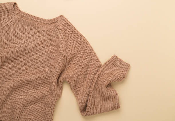 istock Beige knitted sweater on color background, top view 1887938355