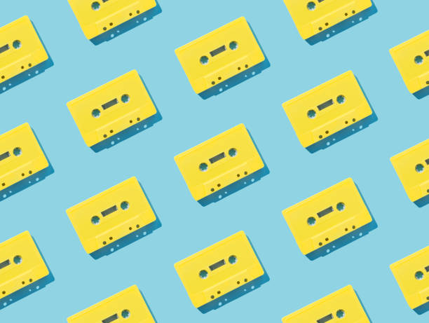 istock Pattern made with retro yellow audio cassette tapes on light blue background. Creative concept of retro technology. 80's aesthetic. Vintage audio cassette tape pattern idea. Retro nostalgia. Flat lay. 1888042908