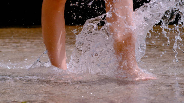 istock CLOSE UP: Water splashes while young barefoot woman crosses shallow alpine river 1888062503