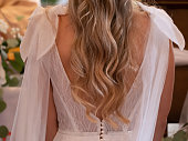 CLOSE UP: Detailed view of the back of young bride at mass in beautiful dress