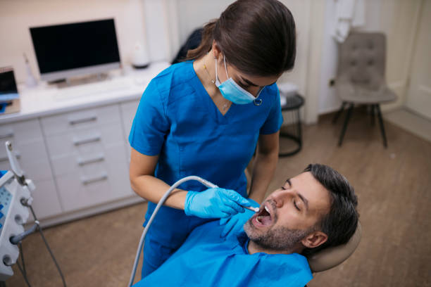 Patient undergoing dental treatment by a female dentist at clinic stock photo