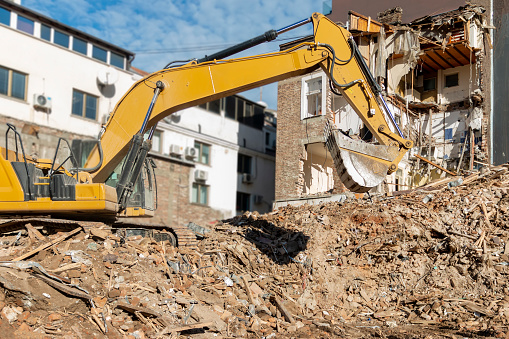 Freeing up space for construction of new building.Process of demolition of old building dismantling. Excavator breaking old house. Destruction of dilapidated housing for new development