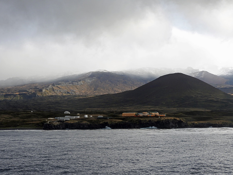 Sub-Antarctic Marion Island basecamp with the island mountains as a backdrop as seen from a distance out on the ocean. Prince Edward Islands, South Africa.
