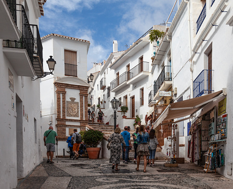 Tourists walking in Calle Hernando el Darra, a stepped street in Frigiliana, one of the famous White Villages of Andalucia, Spain. Frigiliana was voted the prettiest village in Andalucia by the Spanish Tourist Board.