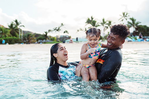 Happy family playing in blue water of swimming pool on a tropical resort at the sea. Focus on children`s hand and splash, shot was taken with waterproof box