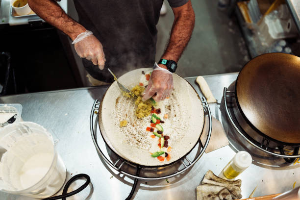 High angle view looking down at a dosa crepe being prepared by a chef in a casual restaurant serving Indian cuisine.