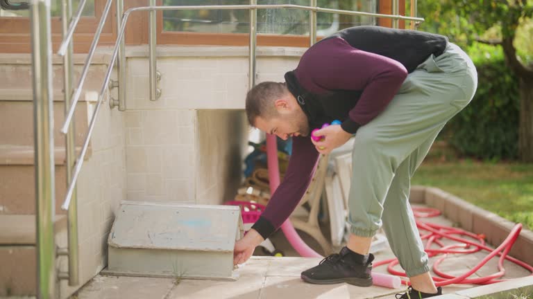 Young man hiding Easter eggs on Easter egg hunt game in back yard garden