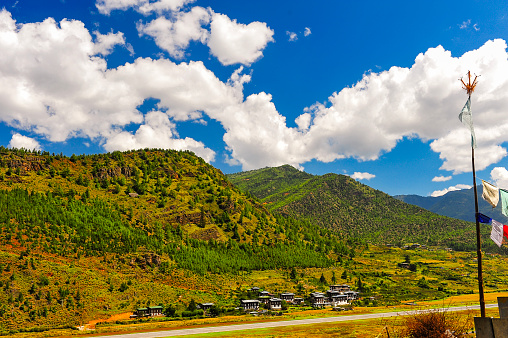 A panoramic view of the airport and the Paro Valley, Bhutan. Landscape with Mountain, river, green meadows and agricultural land, blue sky with white clouds.