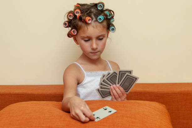 The little girl in hair rollers with game cards.