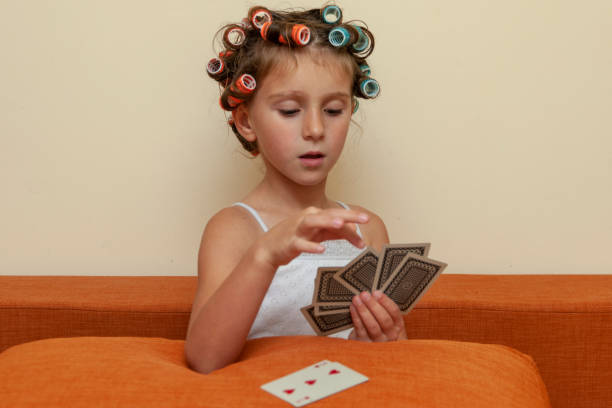 The little girl in hair rollers with game cards.
