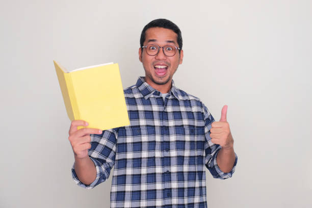 istock Adult Asian man showing amazed expression and give thumb up while holding a book 1888421836