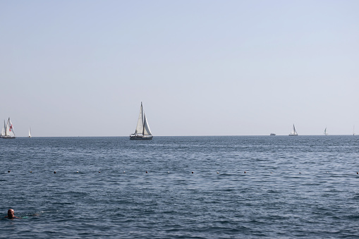 Sailing boats at sea. Water surface and sky in a haze.
