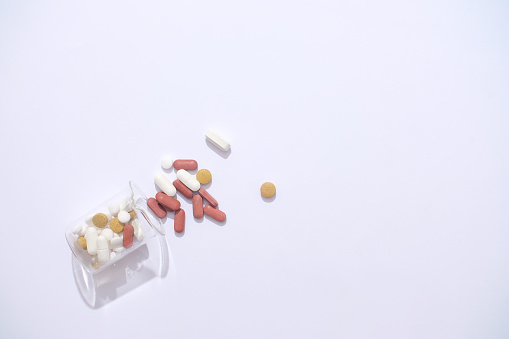Pills are poured from a laboratory beaker on a white background. Medicines have the ability to act directly on pathogens such as bacteria or viruses, thereby reducing the risk of disease.