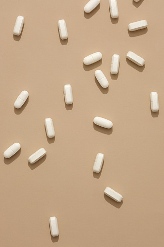 White pills isolated on pastel background. Space for design. Pharmacy theme, medicine tablets. Medicines support disease treatment but should not be abused.