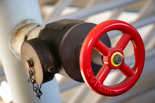 Close-up photo of a red valve attached to a metal pipe.