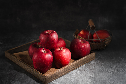 red apples in a wicker basket on dark background