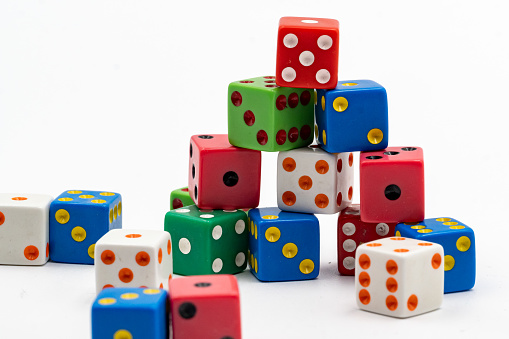 Pile of many different colored dice against a white backdrop