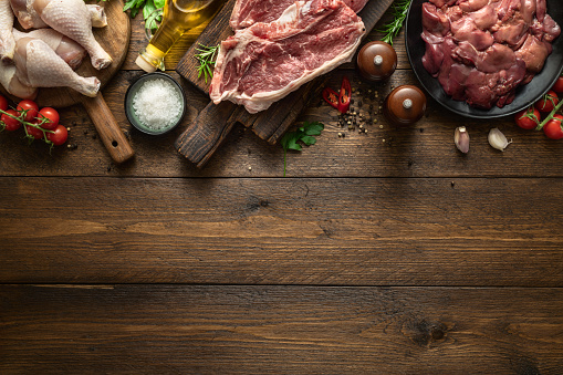 Set of raw ingredients for preparing food, liver, chicken legs and two beef steaks on a wooden background