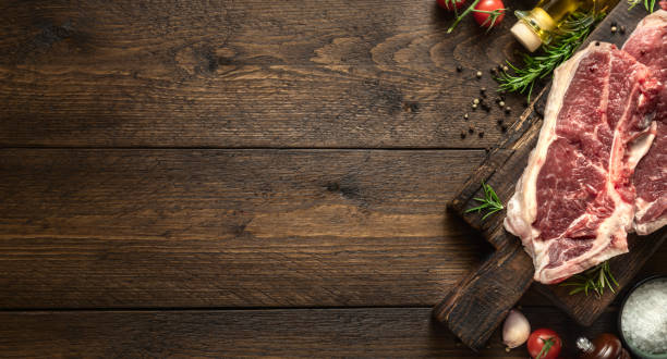 istock Raw beef steak on wooden board on wood table copy space top view 1888817407