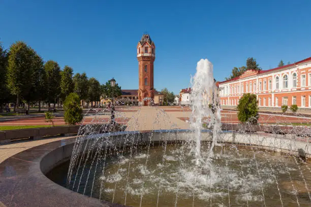 Photo of Old water tower in the city of Staraya Russa. There is a fountain in the foreground