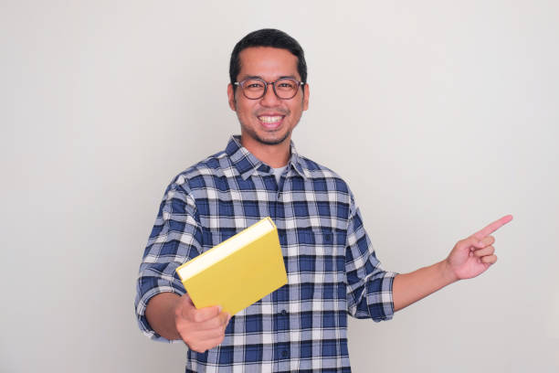 istock Adult Asian man showing wow expression when catching a book that falling from above 1888886761