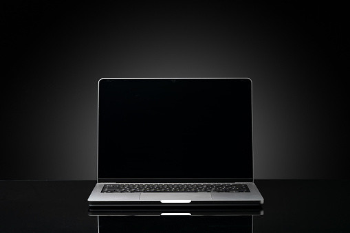 Open laptop with black screen against black background copy space