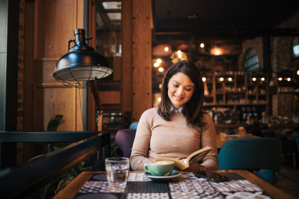 istock Young woman in cafe reading a book 1888953363