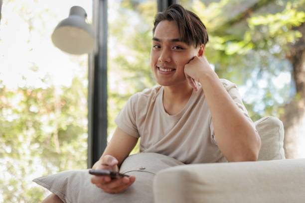 istock Young Asian man on sofa with phone 1888973774