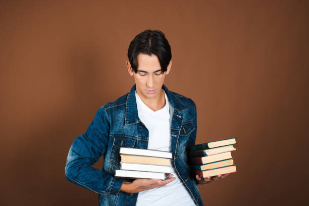 istock Young man and study. Funny attractive guy posing on a brown background. 1889054934