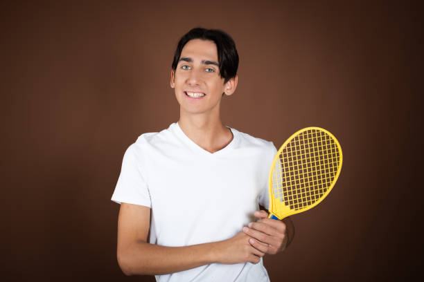 istock Funny guy with children's tennis rackets posing on a brown background. 1889055458