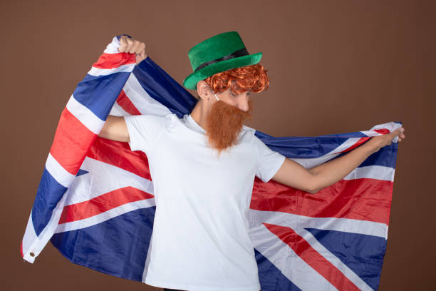 istock St.Patrick 's Day. Funny guy in a leprechaun costume posing on a brown background. 1889060096