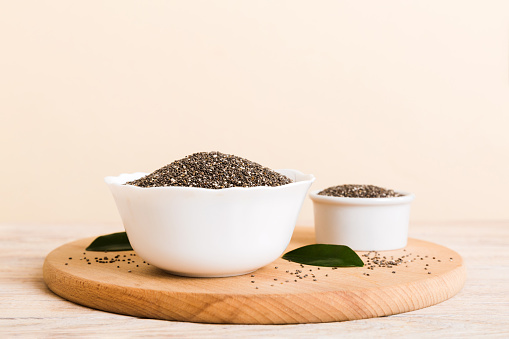 Chia seeds in bowl on colored background. Healthy Salvia hispanica in small bowl. Healthy superfood.