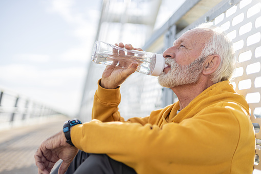 Senior athlete resting after outdoor exercise and drinking water