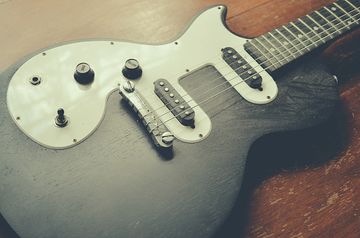 Vancouver, BC, Canada - August 31, 2012: Two maple Fender Stratocasters with focus on the nearer Guitar headstock. Photographed in black and white on a gray background.