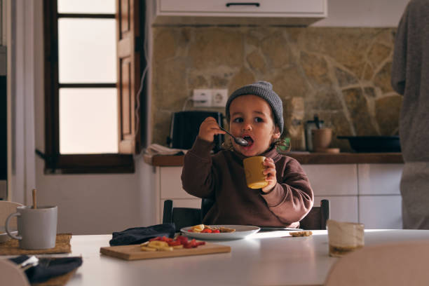 istock Cute boy eating from spoon and cup in kitchen 1889137247