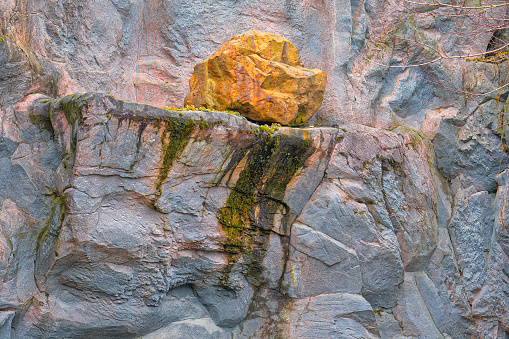 Deep forest. Deserted places. On the ledge of a stone mountain lies a huge boulder.