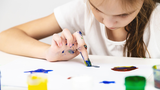 children's creativity. girl painting picture draws with fingers on white background