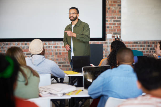 istock College teacher smiling during a lesson with students in a classroom 1889229321