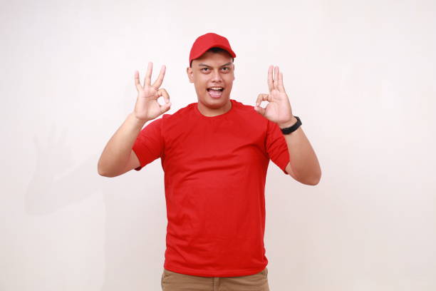 istock Handsome young asian courier standing while showing okay hands gesture against white background 1889235311