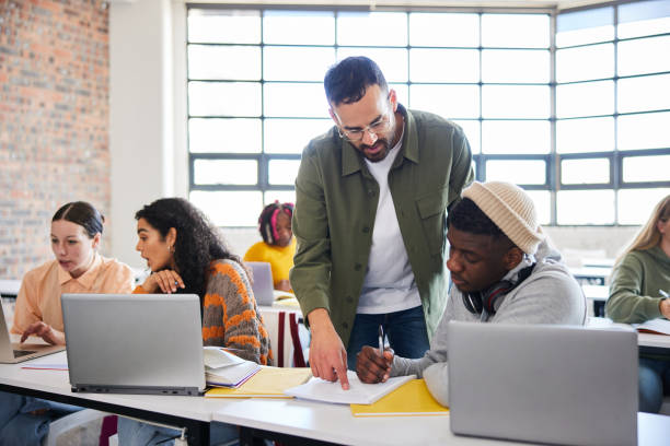 Teacher helping a male college student during a class - fotografia de stock