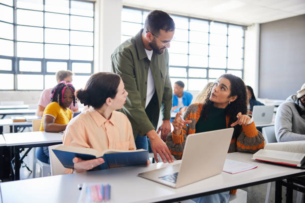 istock Teacher helping a two female college students during a class 1889236448