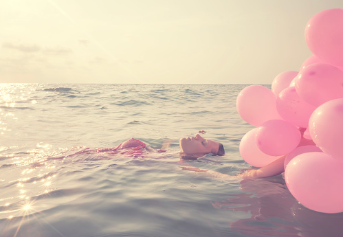 young woman with balloons at the water