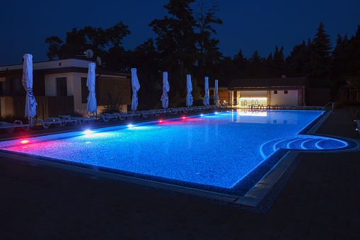 Summer outdoor pool with lighting at night. Relaxation in a countryside holiday complex.