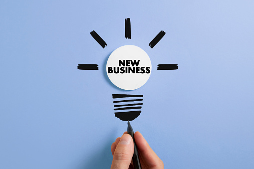 New idea and business concept with human hand drawing idea bulb on blue background