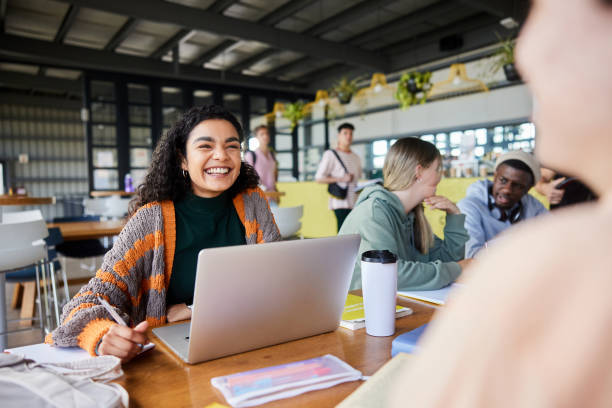 istock Smiling college student talking with a friend while working on a laptop 1889357304