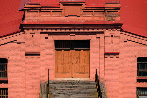 seaport, Odessa, Ukraine, May 4, 2019 - the facade of an old industrial building, brick walls painted red, red roof, wooden door for the entrance to the building