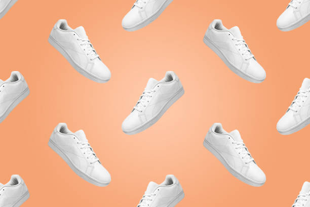 istock Pattern of white sneakers isolated on peach color (peach color) background. 1889380764