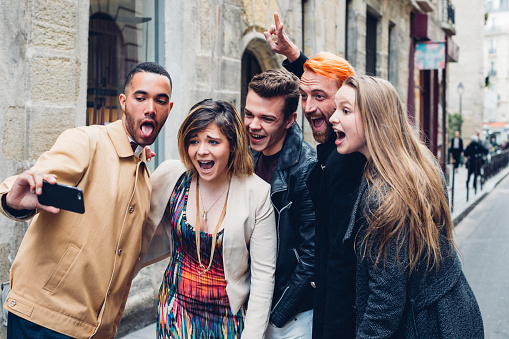Friends capturing memories with a group selfie amidst their Parisian adventure using a smartphone